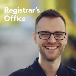 A smiling student wearing glasses stands outdoors with blurred greenery in the background. The words “Registrar’s Office” appear beside him.